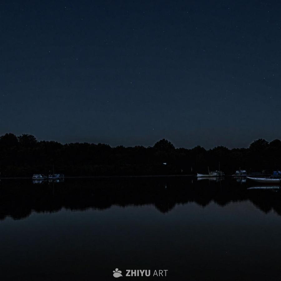 平静的湖面在夜间，上方是漆黑的夜空。湖水静止，反映