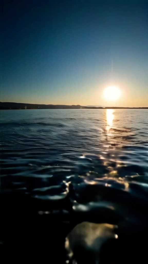 太阳正落在平静的海面上，海面上有波纹，远处有陆地。