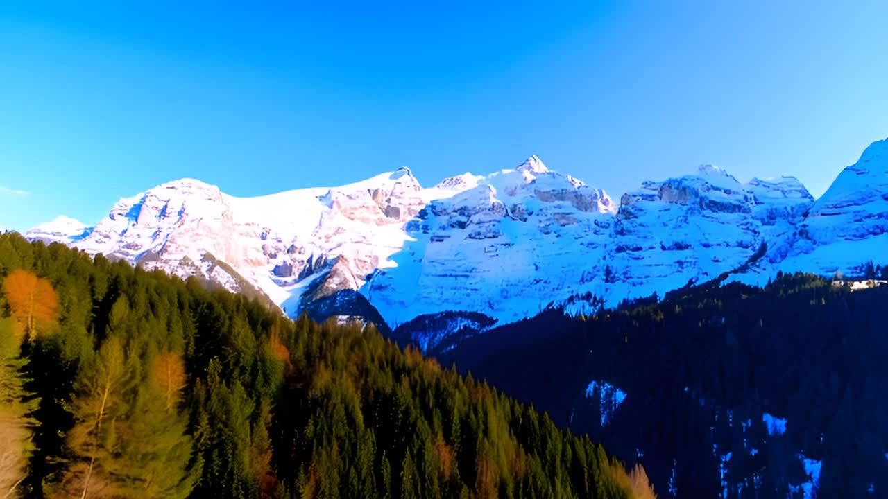 被雪覆盖的山峰在晴朗的蓝色天空下延伸，山峰下方是茂
