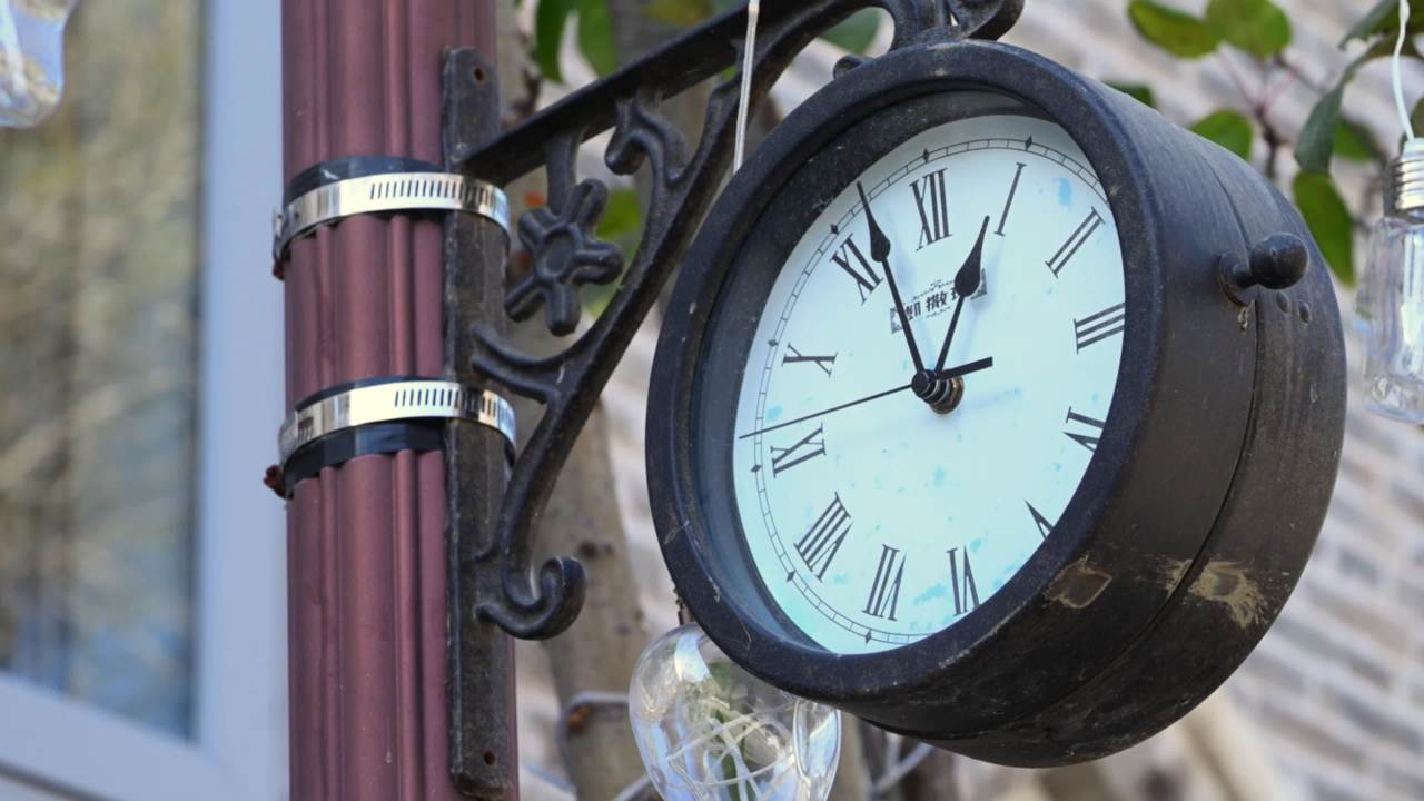 灯杆上复古式罗马数字钟表灰色砖墙背景