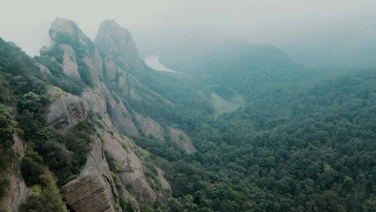 航拍雾中江西上饶弋阳龟峰景区丹霞地貌的石柱山体和森林 1