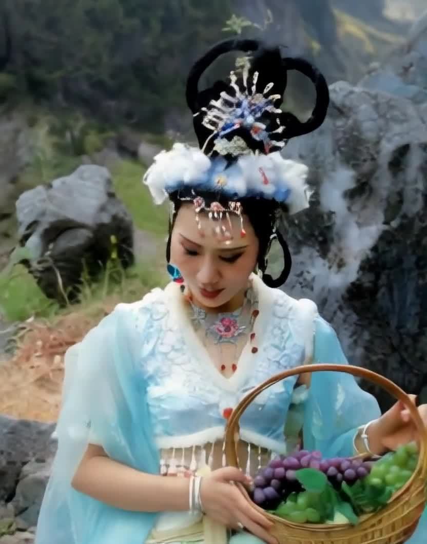 古装女子提葡萄篮立于山石旁