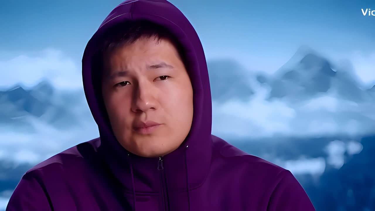 紫色的连帽衫男子直视镜头，表情沉思，脸部被柔和的人