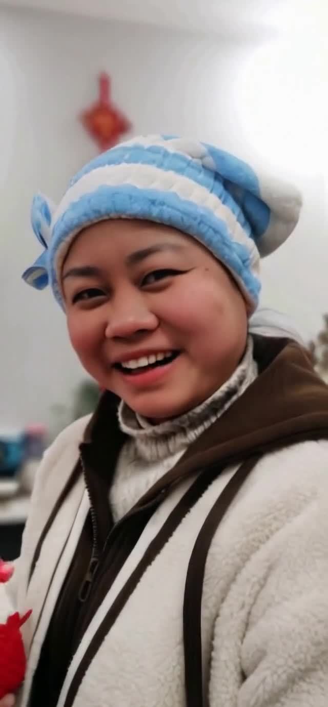 戴蓝白帽子的微笑女性，穿着毛绒外套。