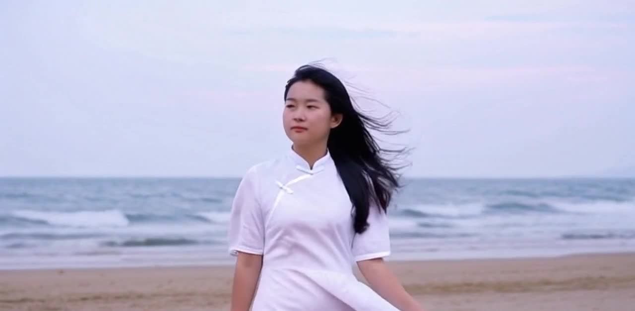 海边身着白色连衣裙的年轻女性，迎风而立