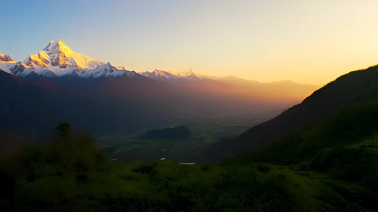 雪山山峰在夕阳的照耀下呈现金色，山谷郁郁葱葱，远处