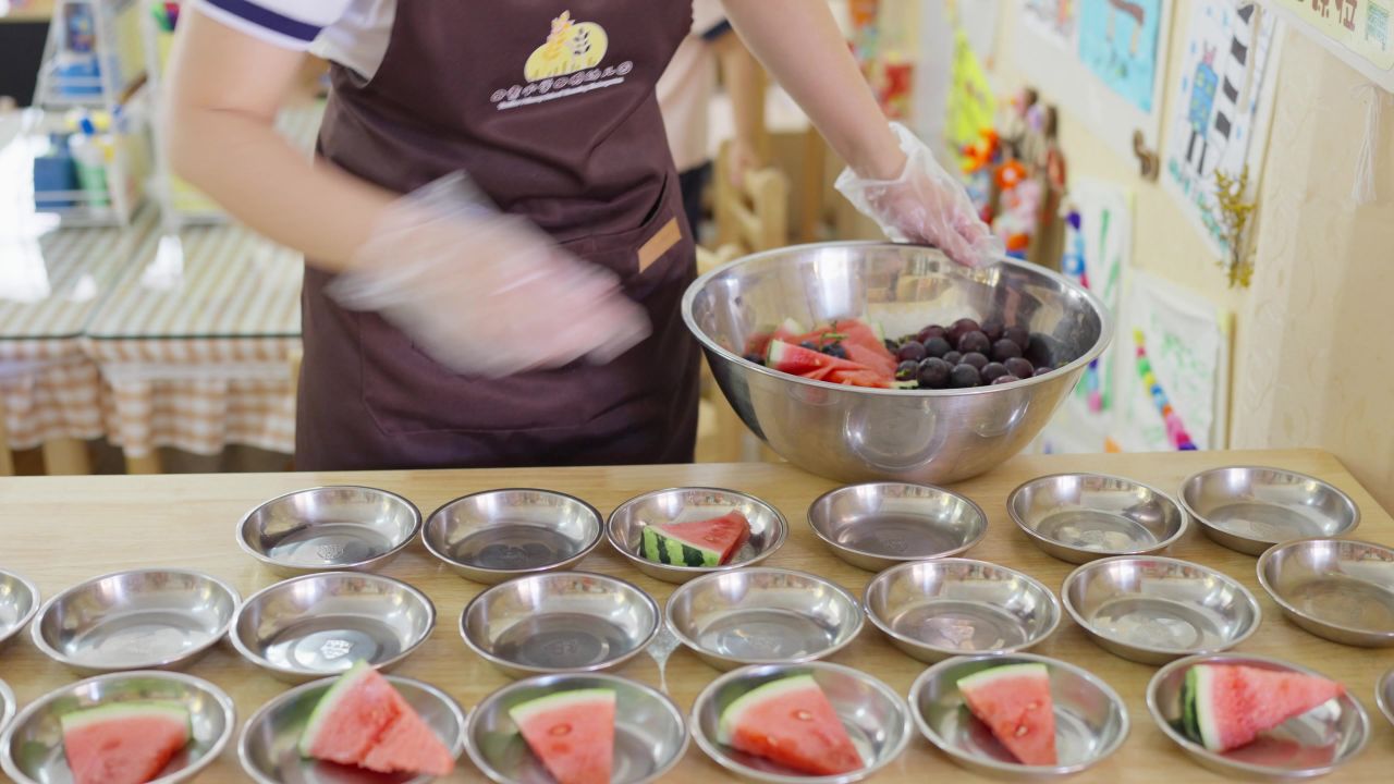 幼儿园保育员为孩子们准备水果餐