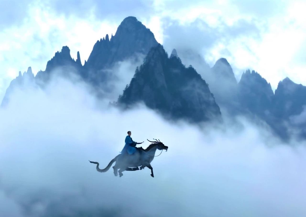 一名身穿蓝色长袍的人骑在一只类似龙的生物上，在云雾