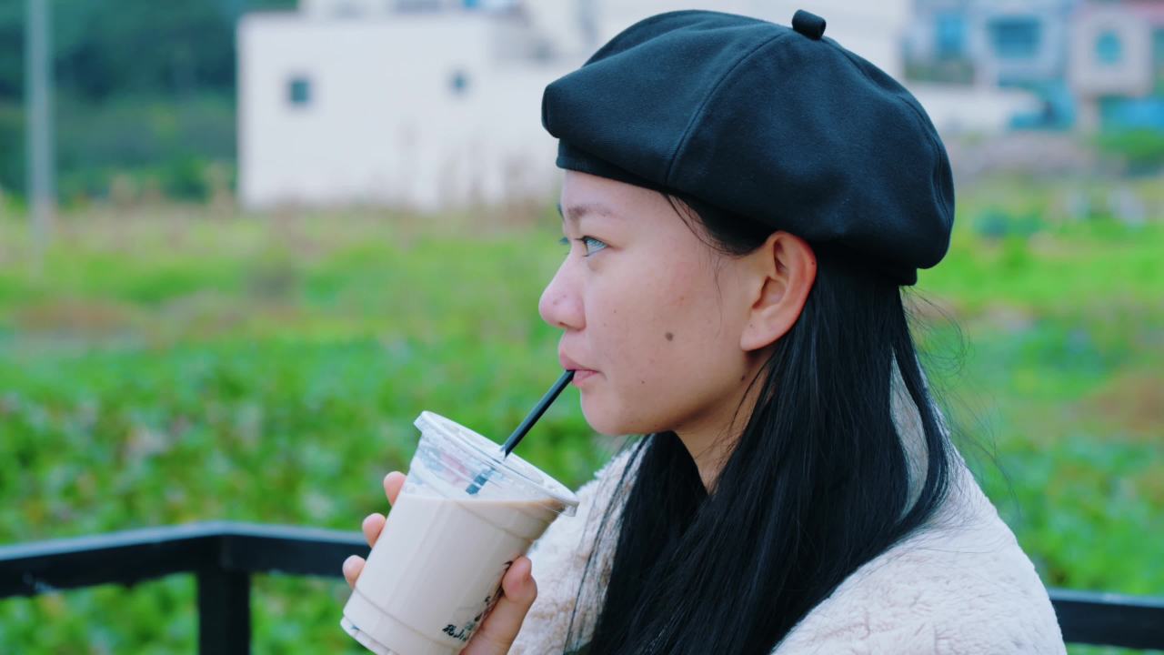 戴贝雷帽的女子喝奶茶