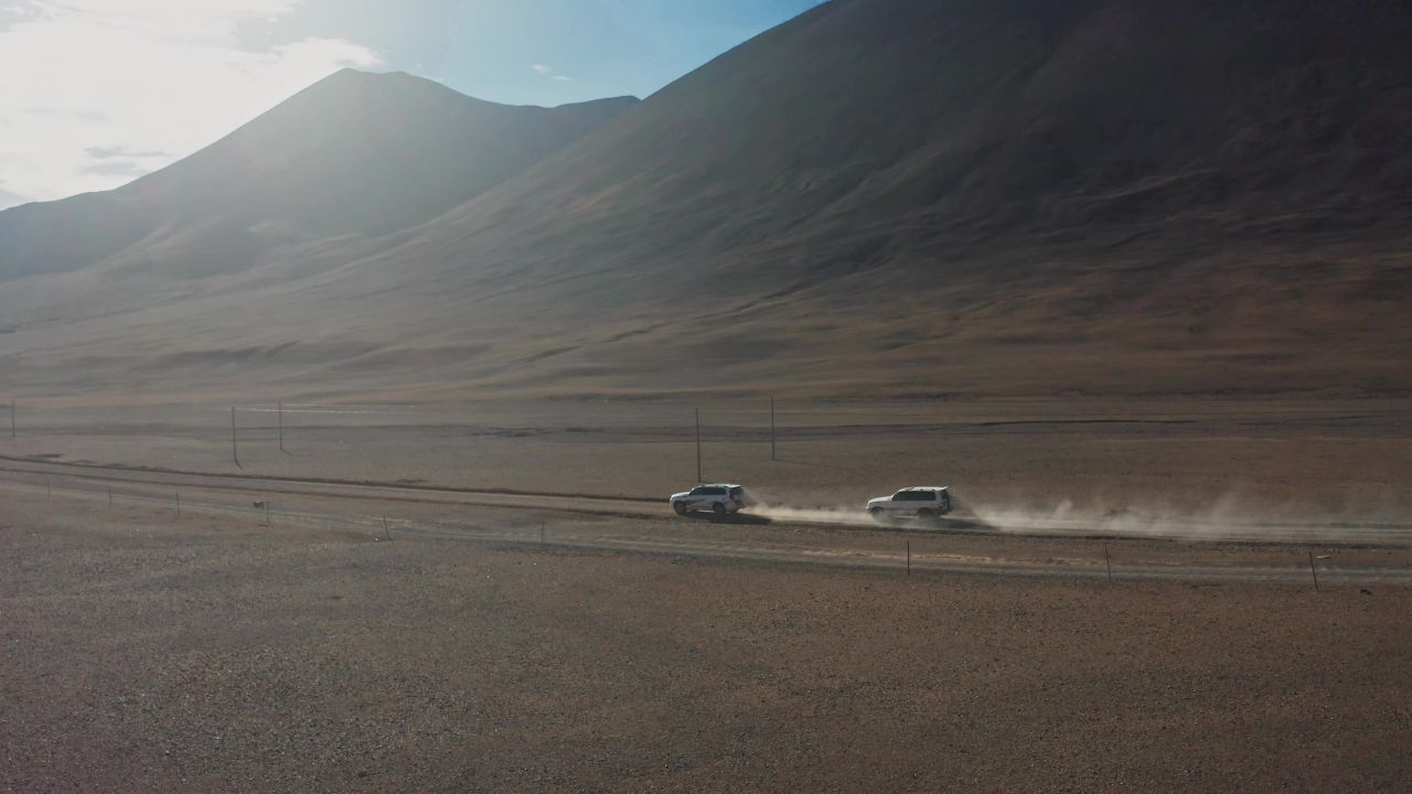 航拍越野车行驶在西藏阿里无人区的荒漠中，车后扬起尘烟