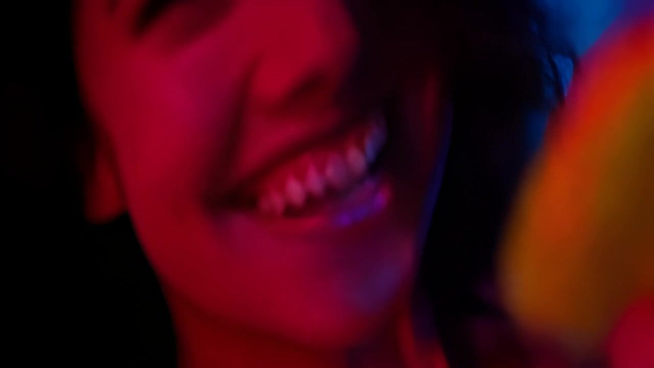 一个女人的脸部特写，她正在微笑和跳舞。镜头有轻微的