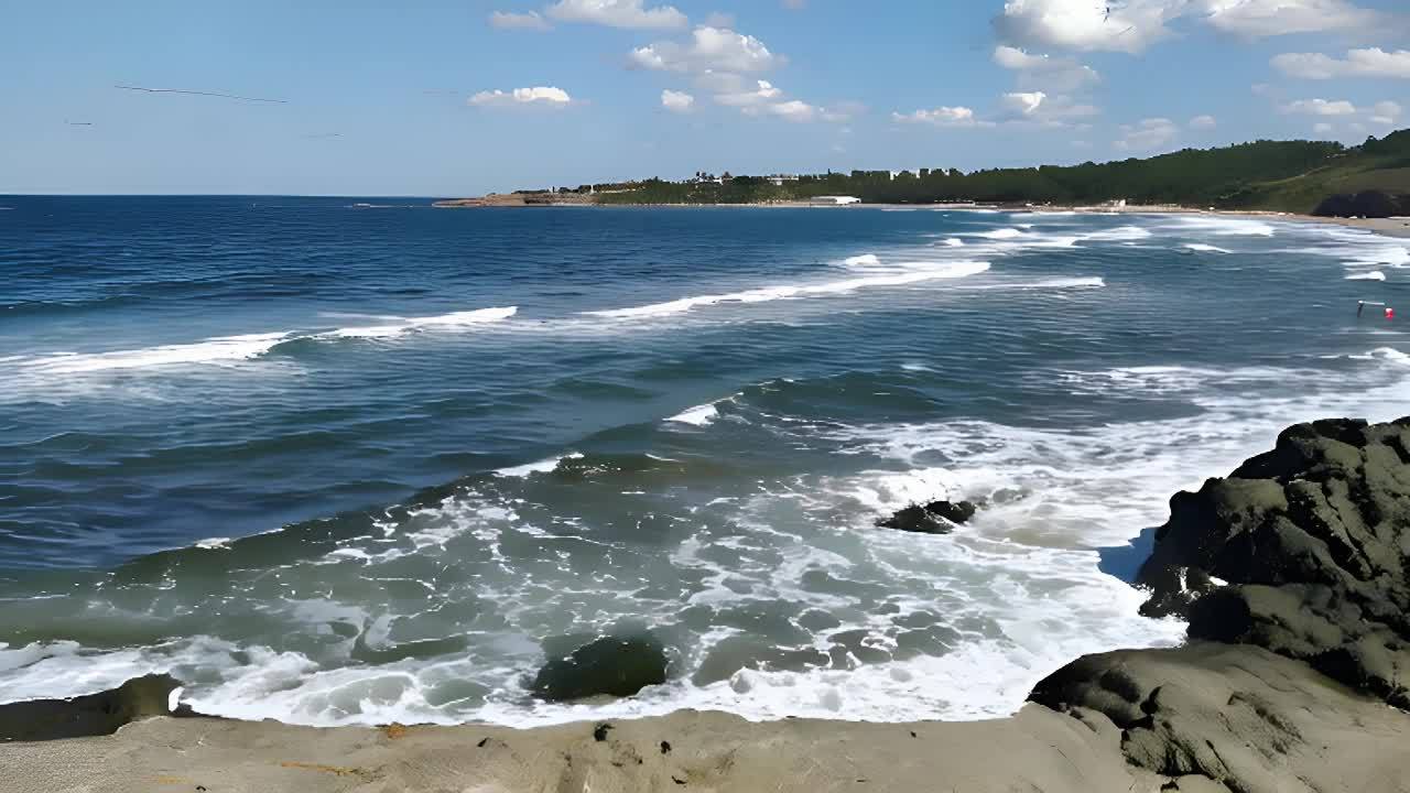 海面上有轻微的波纹，天气晴朗。海滩上有海浪，岸边有