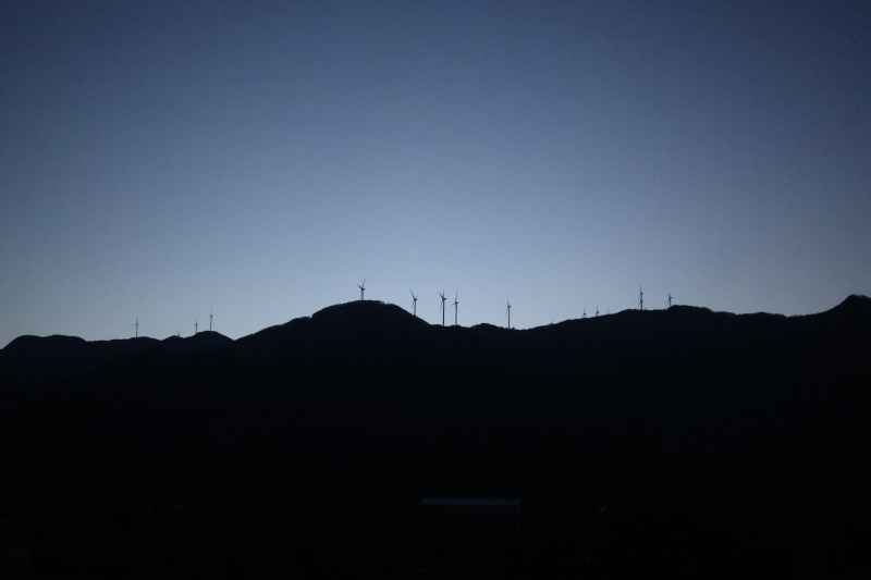 晴朗傍晚的山坡与山顶风电剪影