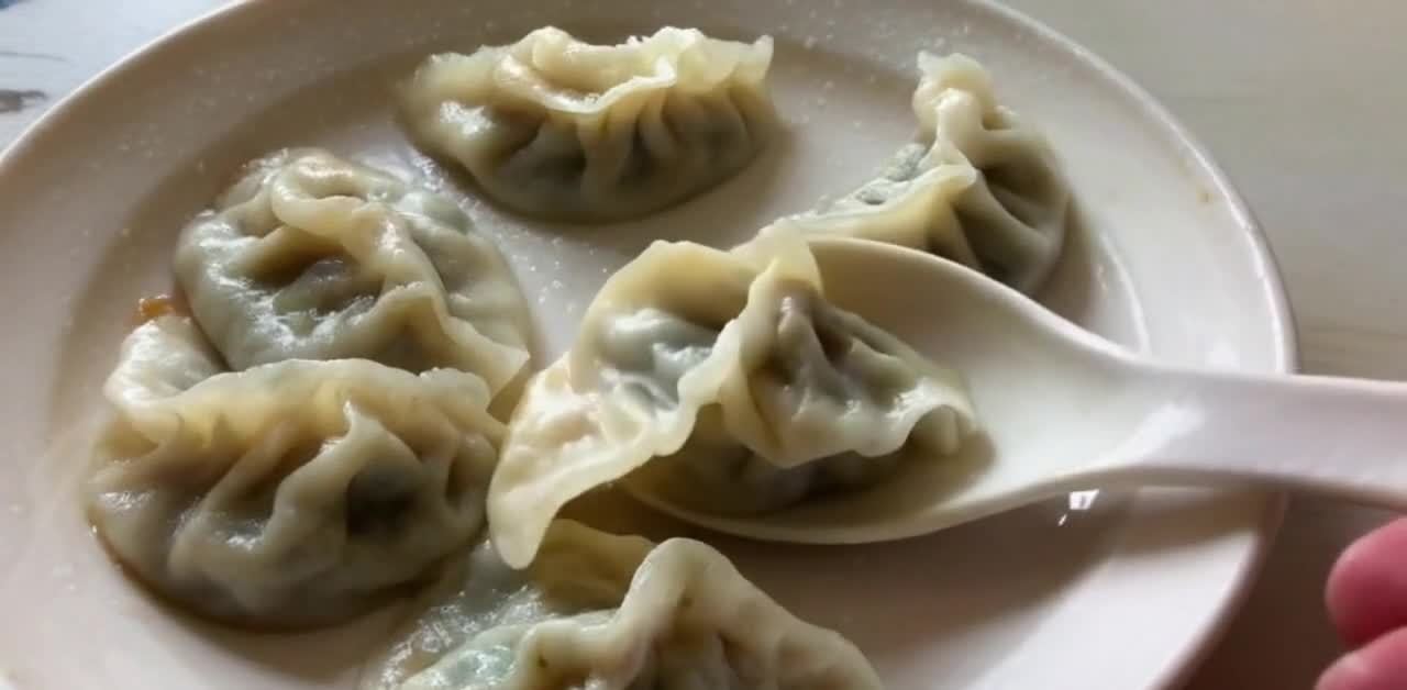 盘子中盛放着几个煮熟的饺子，饺子呈白色，外形饱满，