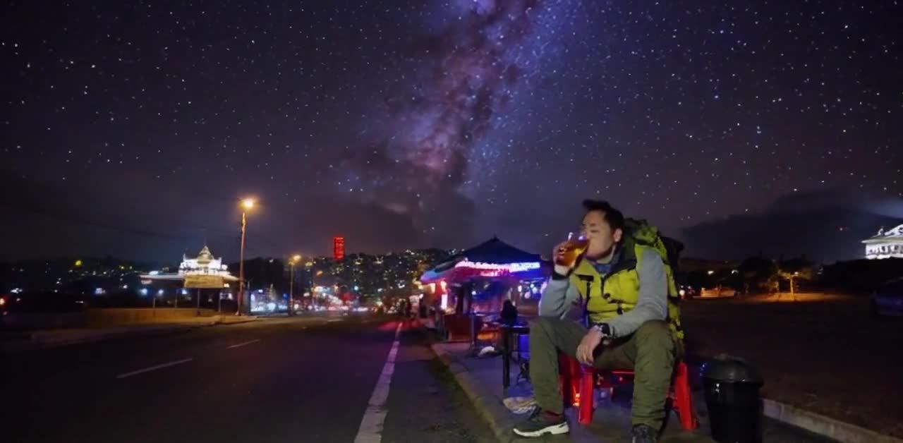夜幕降临，天空中有繁星点缀，远处霓虹灯闪烁，城市夜