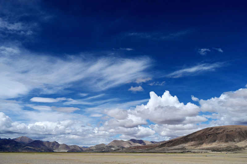 西藏阿里地区蓝天白云下广袤的草原和山脉