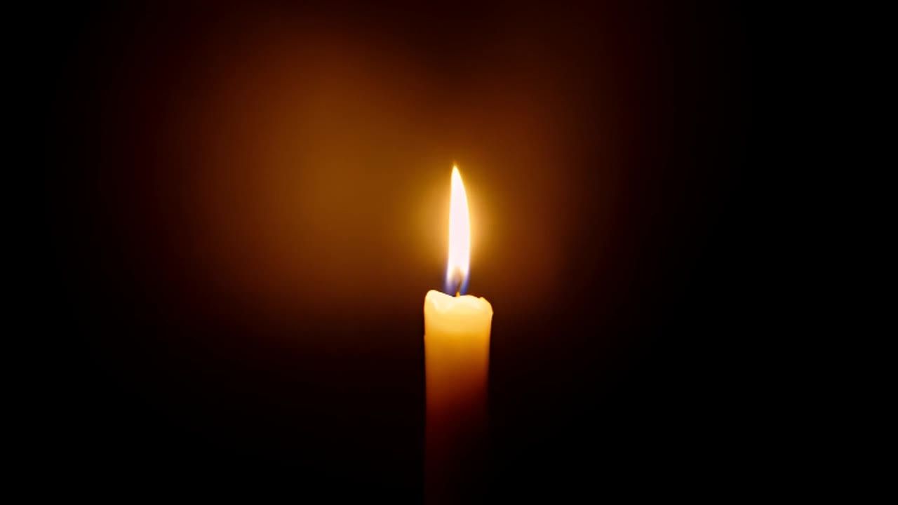一支摇曳的蜡烛从黑暗中浮现。火焰轻盈地跳动着。柔和