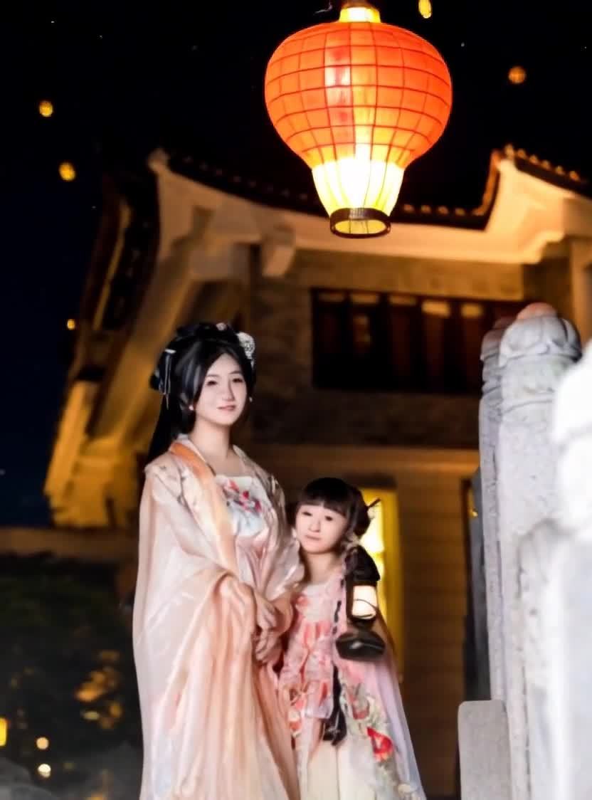 两名身穿汉服的女子对视着，背景是夜空和古建筑。夜空