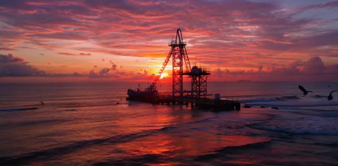 海上钻井平台在海中，一个类似起重机的结构延伸到水面