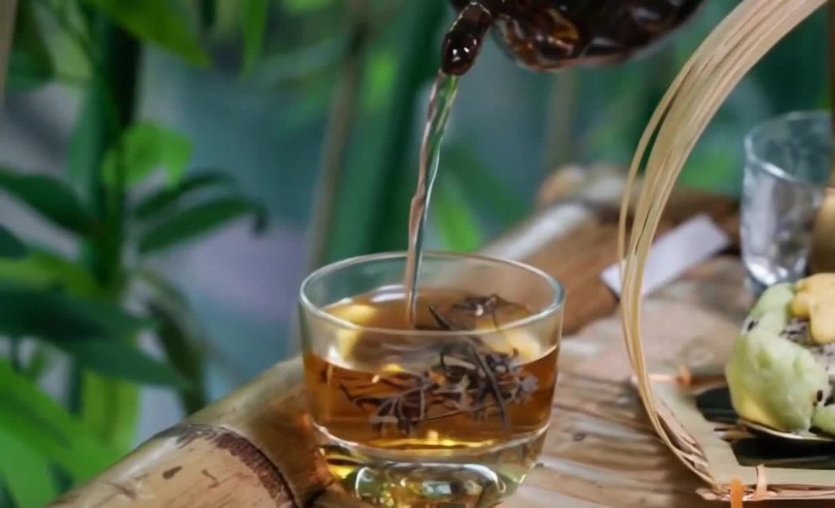 茶水倾入玻璃杯，竹制平台上的静物摆设。