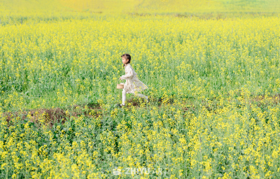 小女孩奔跑在油菜花丛中